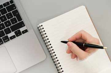 female hand with pen and computer gray background
