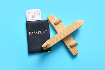 Wooden toy plane, passport and ticket on color background