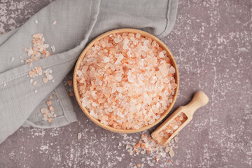 Wooden bowl and scoop with Himalayan pink salt on dark table
