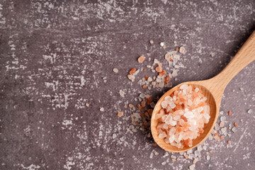 Wooden spoon with Himalayan pink salt on dark background