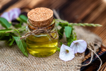 Convolvulus arvensis, or field bindweed near a medicine vial with a cork stopper with an elixir from an infusion of herbs.