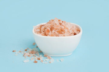 Bowl with Himalayan pink salt on blue background