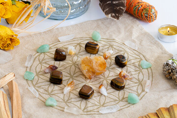A top view image of a crystal healing grid with sage smudge sticks and yellow roses. 