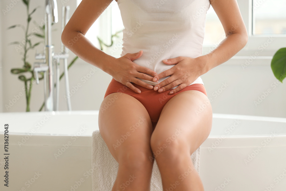 Wall mural Young woman wearing red menstrual panties in bathroom, closeup