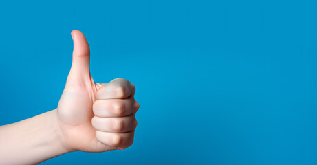 A woman's hand giving a thumbs-up gesture as a sign of approval or liking.