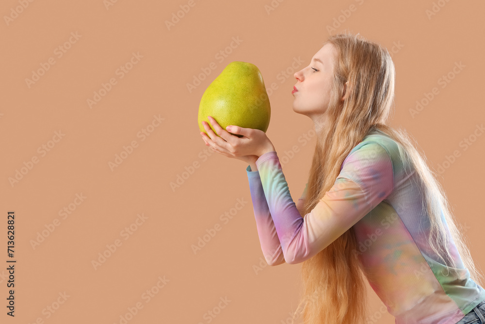 Sticker young woman with pomelo blowing kiss on beige background