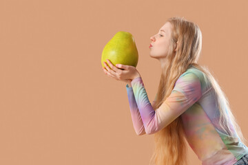 Young woman with pomelo blowing kiss on beige background
