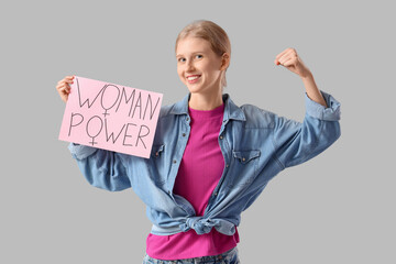 Young girl holding paper with text WOMAN POWER on light background