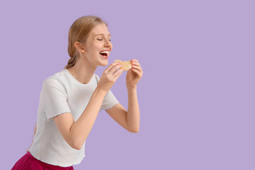 Young woman eating pomelo on lilac background