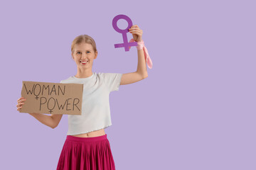 Young girl holding paper with text WOMAN POWER and gender symbol on lilac background