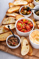 Dips and snacks board with toasted baguette, pimento cheese, olives and tomatoes