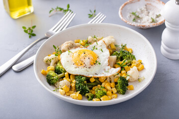 Healthy breakfast with cooked vegetables and fried egg on top