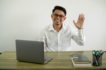 young asian businessman in a workplace saluting with hand with happy expression wear white shirt with glasses isolated