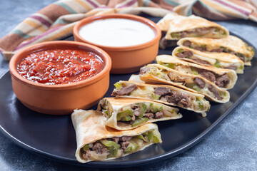 Fajita quesadilla with pieces of beef steak, green bell pepper, onion and cheese, on a plate