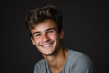 A young man in a grey shirt smiles for the camera