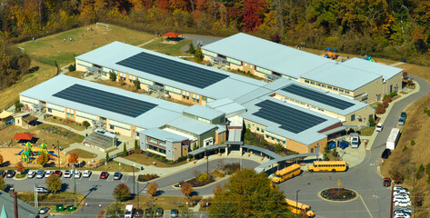 Aerial view of american school building with rooftop covered with photovoltaic solar panels for...