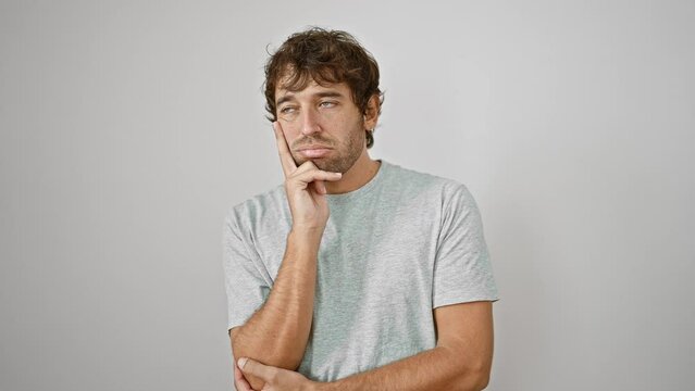 Young, bored-looking man in t-shirt, arms crossed, tired from battling depression, lost in thought over white isolated background.