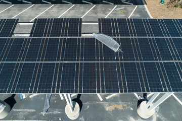 Destroyed by hurricane wind solar panels installed over parking lot canopy shade for parked cars...