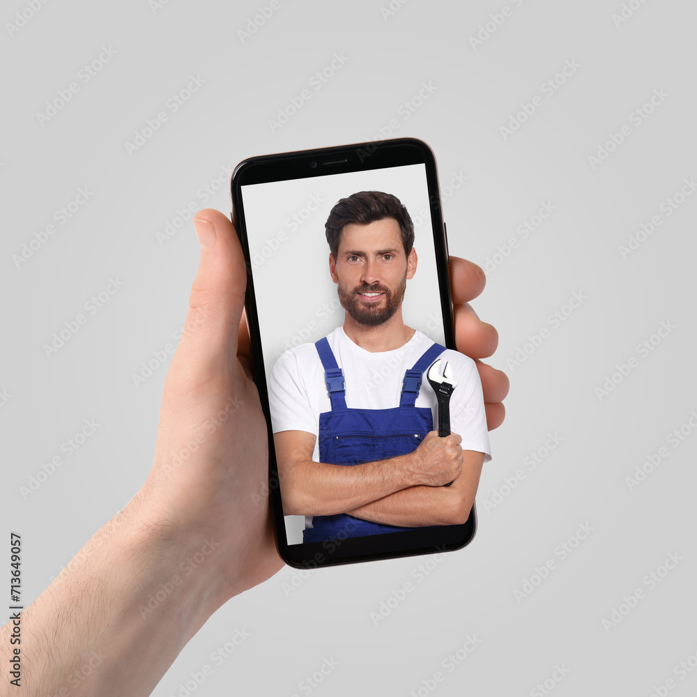 Poster find plumber. man using mobile phone on light grey background, closeup. specialist looking out of ga