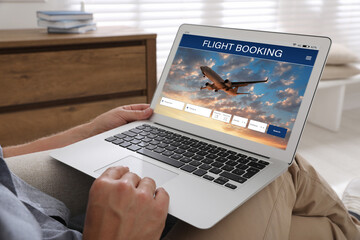 Fototapeta na wymiar Man using laptop to book flight at home, closeup
