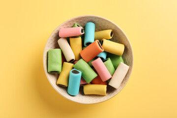 Bowl of tasty liquorice candies on yellow background, top view