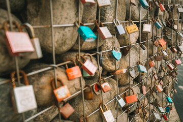 Metal locks on a grid with stones on the promenade by the sea. Customs and traditions of lovers and...