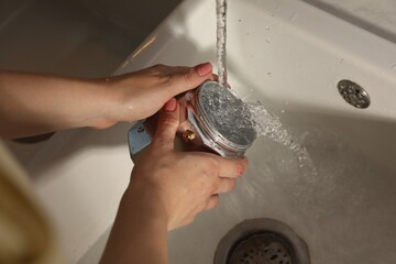 Woman washing moka pot at sink in kitchen, closeup