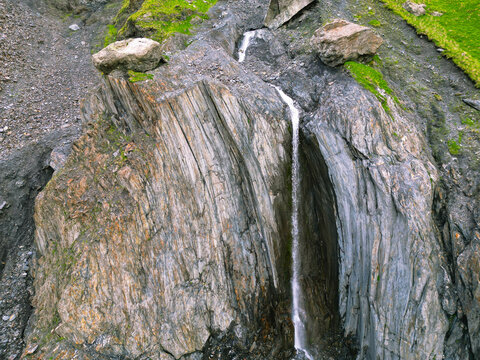 waterfall among green mountains hills - drone photo.