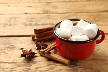 Tasty hot chocolate with marshmallows and spices on wooden table, closeup. Space for text