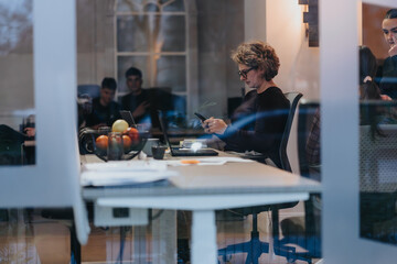 A dedicated professional woman concentrates on her work at a modern office desk, indicating productivity and commitment.