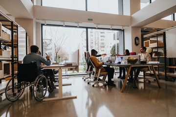 A multiracial group of employees collaborates around a table in a well-lit office space, showcasing wheelchair accessibility and teamwork. - Powered by Adobe