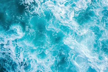Fotobehang From above aerial view of turquoise ocean water with splashes and foam for abstract natural background and texture. © Hunman