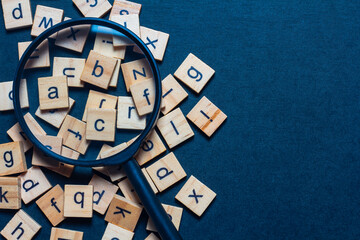 English letters made from square wooden tiles There are English letters scattered on a black background. Concepts for developing grammar thinking