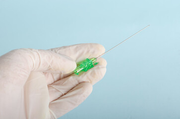 Needles for canalization in hands of doctor with white gloves isolated on light blue background....
