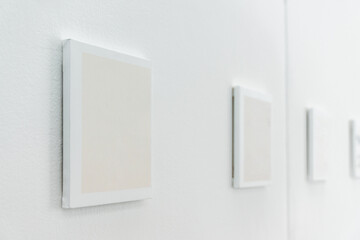 Roll of white blank canvas picture frame mockup hanging on white wall.	