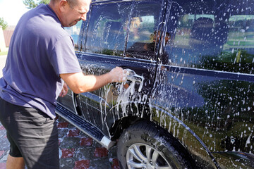 man washing car with car wash - pressure washer , shampoo, sponges and microfiber car towels