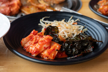 Korean side dishes, kimchi, seasoned bean sprouts, sesame leaves marinated in sauce