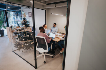 Diverse business team discussing market research, project planning, and digital marketing strategies in a creative office.