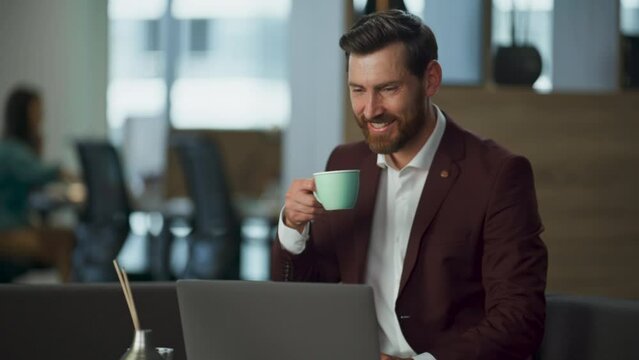Smiling lawyer drinking coffee in luxury cabinet closeup. Joyful man work laptop
