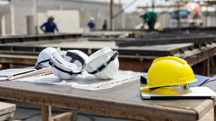 A set of helmet and safety vest left on prefab floor in a factory ready to be used by foremen or...