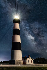 In the Outer Banks of Cape Hatteras, North Carolina, near Nags Head, the black and white striped Bodie Island Lighthouse shines under a night sky full of stars with the Milky Way Galaxy visible. - 713691029