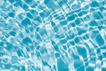Bluewater waves on the surface ripples blurred. Defocus blurred transparent blue colored clear calm water surface texture with splash and bubbles. Water waves with shining pattern texture background.