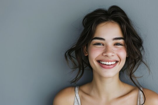 Young woman's cheerful smile, grey backdrop, copy space