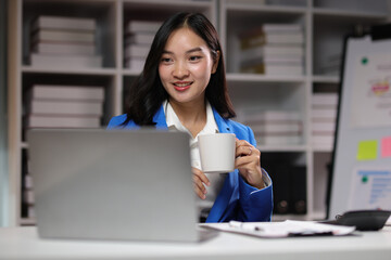 Attractive Asian businesswoman working overtime with documents on desk in office.