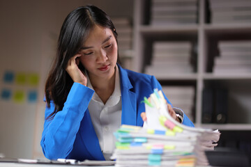 Young Asian businesswoman working with work document paperwork during the night, working overtime...