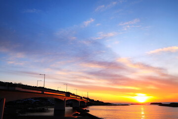 夕日に染まる橋と海に沈む夕日