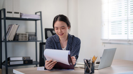 Businesswoman reading to checking financial document and thinking about investment of business project to writing data in paper while working and analysis about strategy marketing of new business