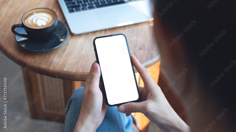 Wall mural cell phone white screen mockup, woman hand holding mobile phone with blank screen while working at c