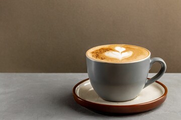 Cup of cappuccino on the table, gray and brown background, copy space