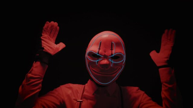 Closeup footage of pantomime artist with scary mask and creepy moves on black background
